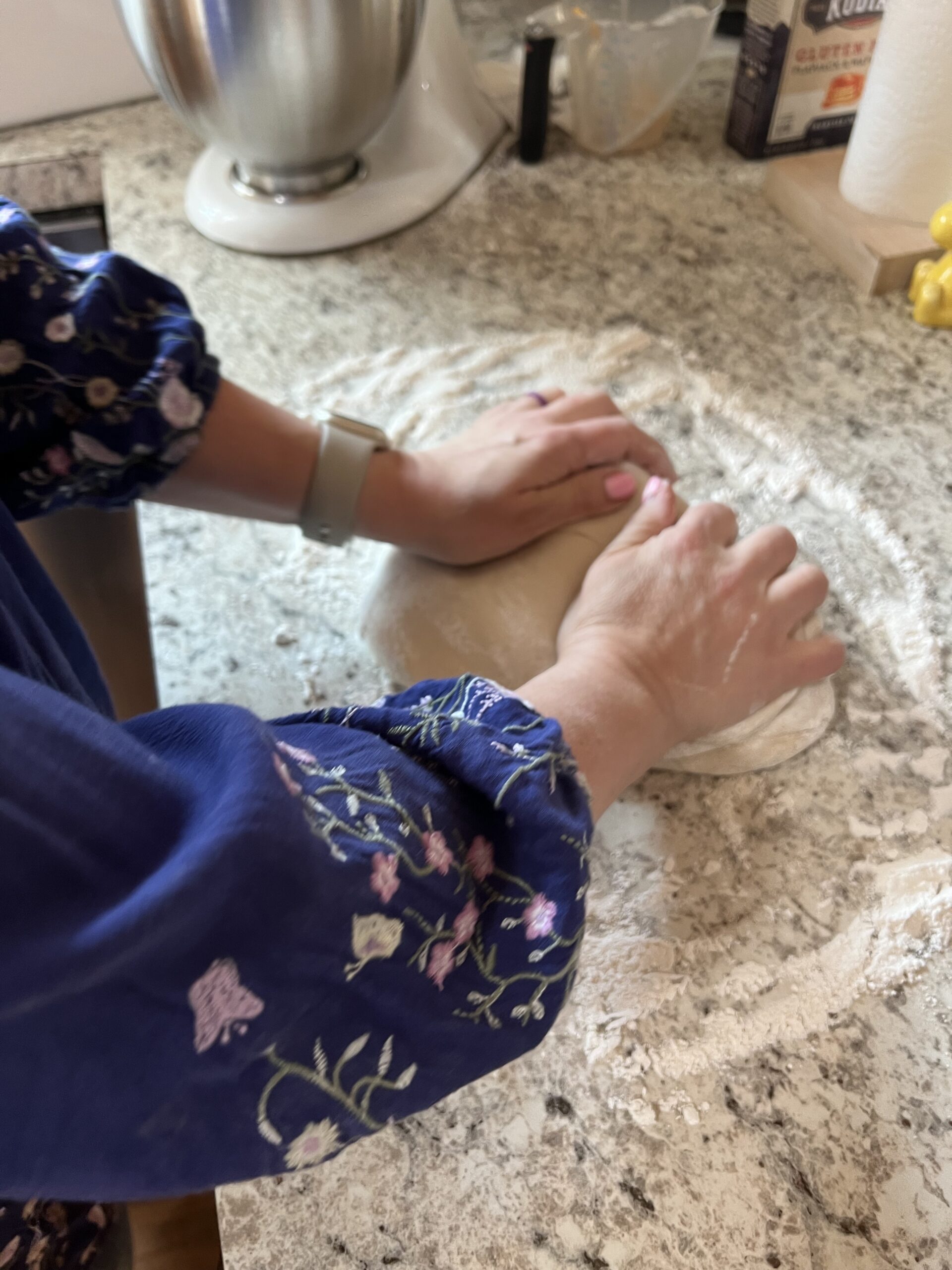 woman with blue floral top shaping loaf of dough
