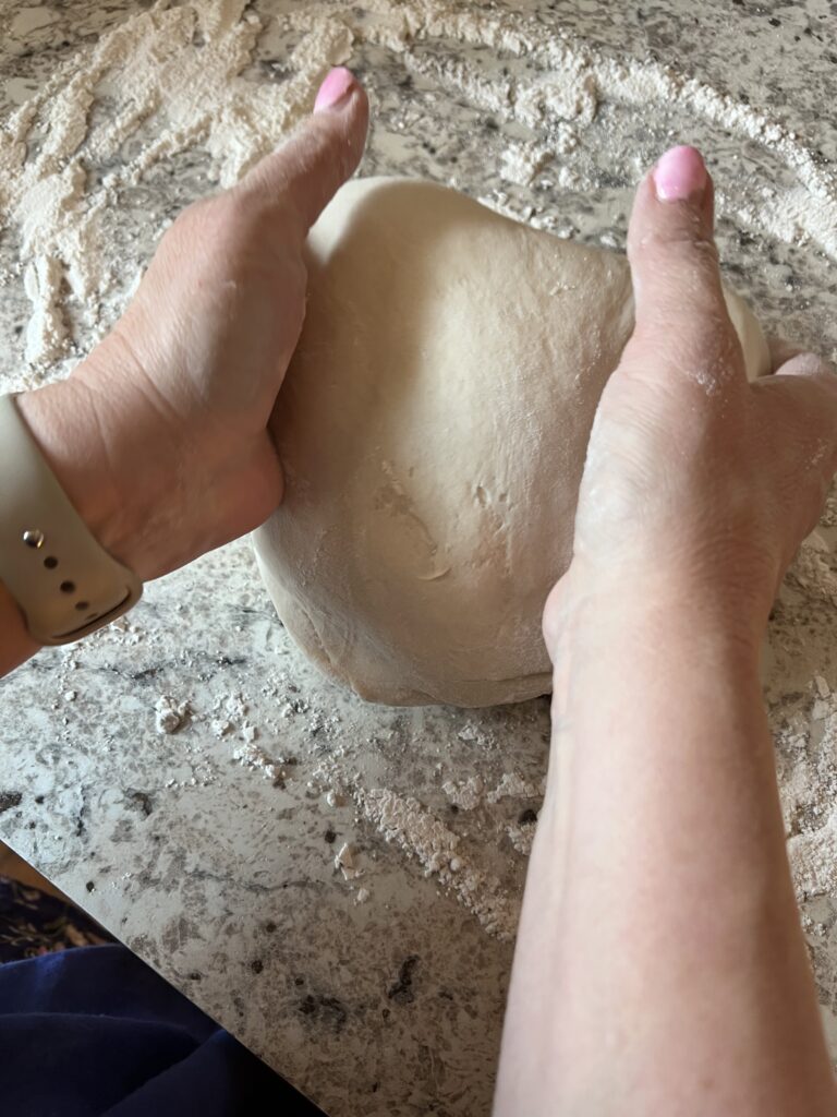 woman's hands shaping ball of pizza dough