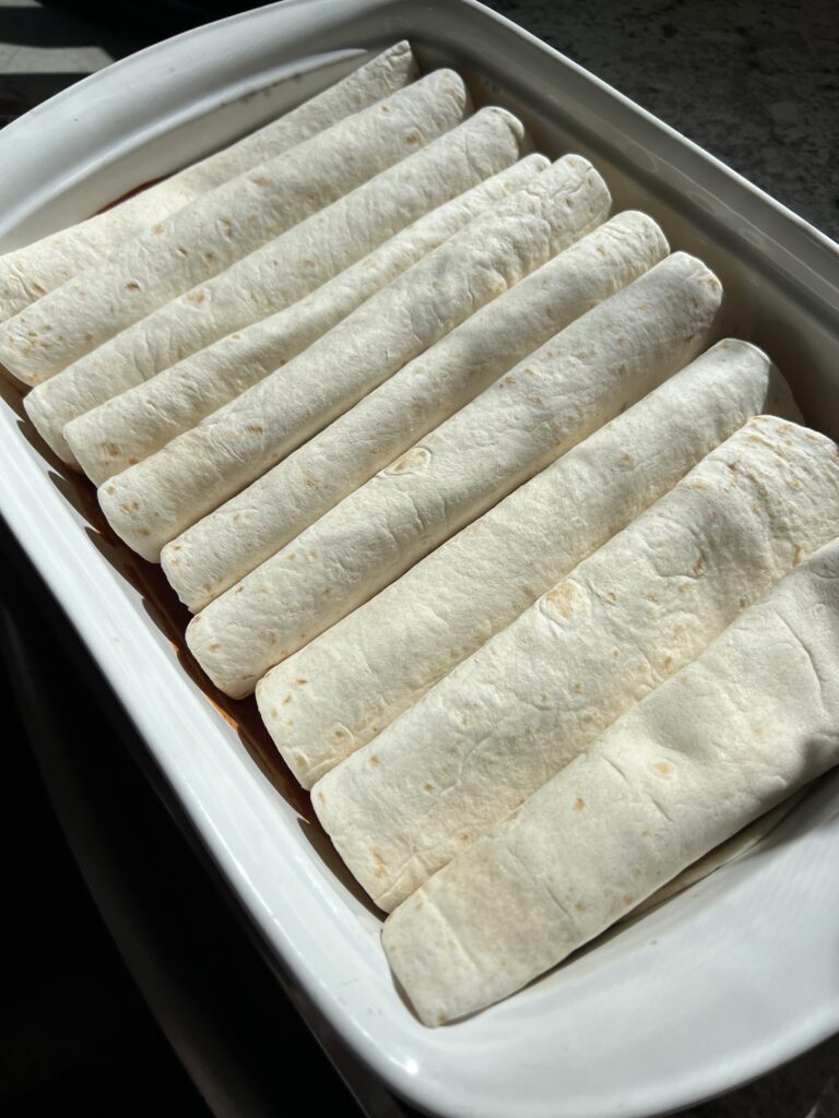 enchiladas arranged seam side down in 9x13 baking dish