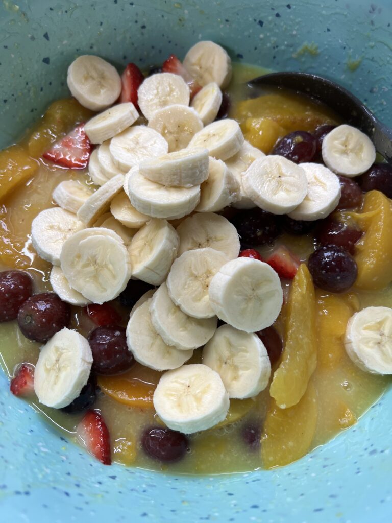fruit salad ingredients in aqua pioneer woman mixing bowl ready to be stirred