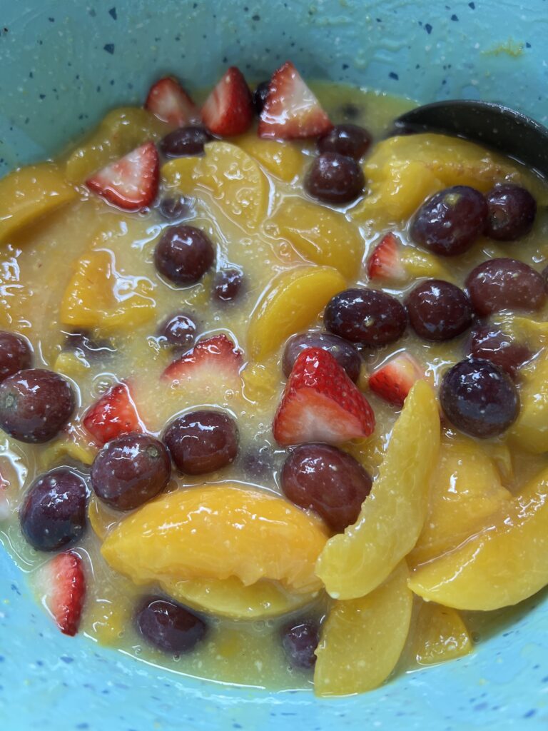 canned peaches, strawberries, red seedless grapes all mixed together in aqua pioneer woman mixing bowl